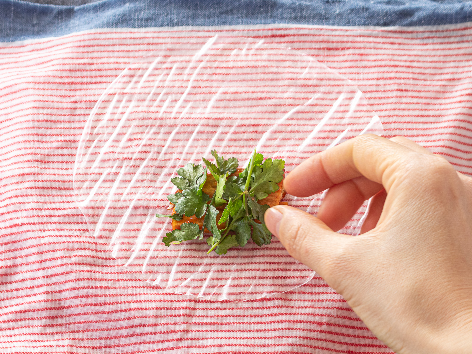 さつまいもの上にパクチーをのせる様子。野菜だけの生春巻きを作る工程