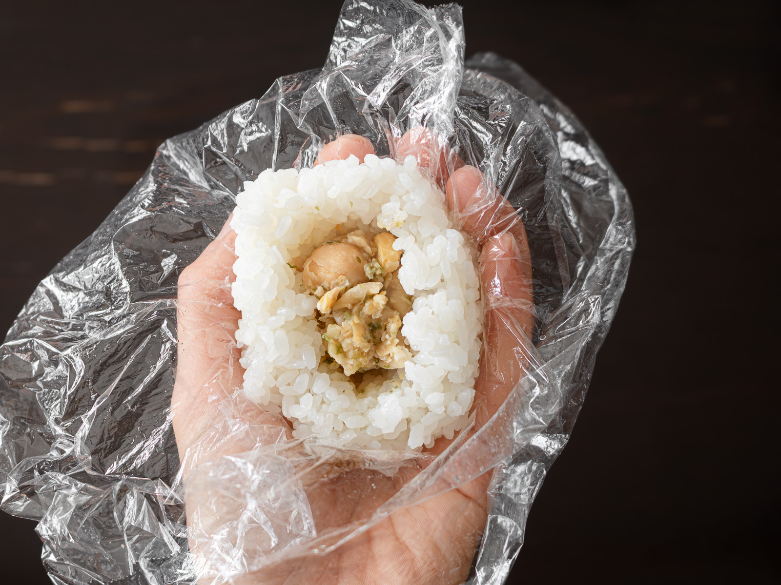 ラップで包みながらおにぎりをまとめる