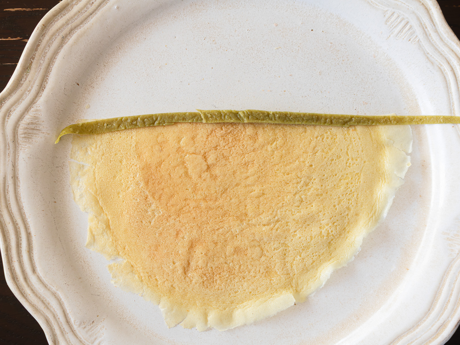 薄焼き卵をカットして着物の形に準備し、抹茶生地を襟として重ねた様子