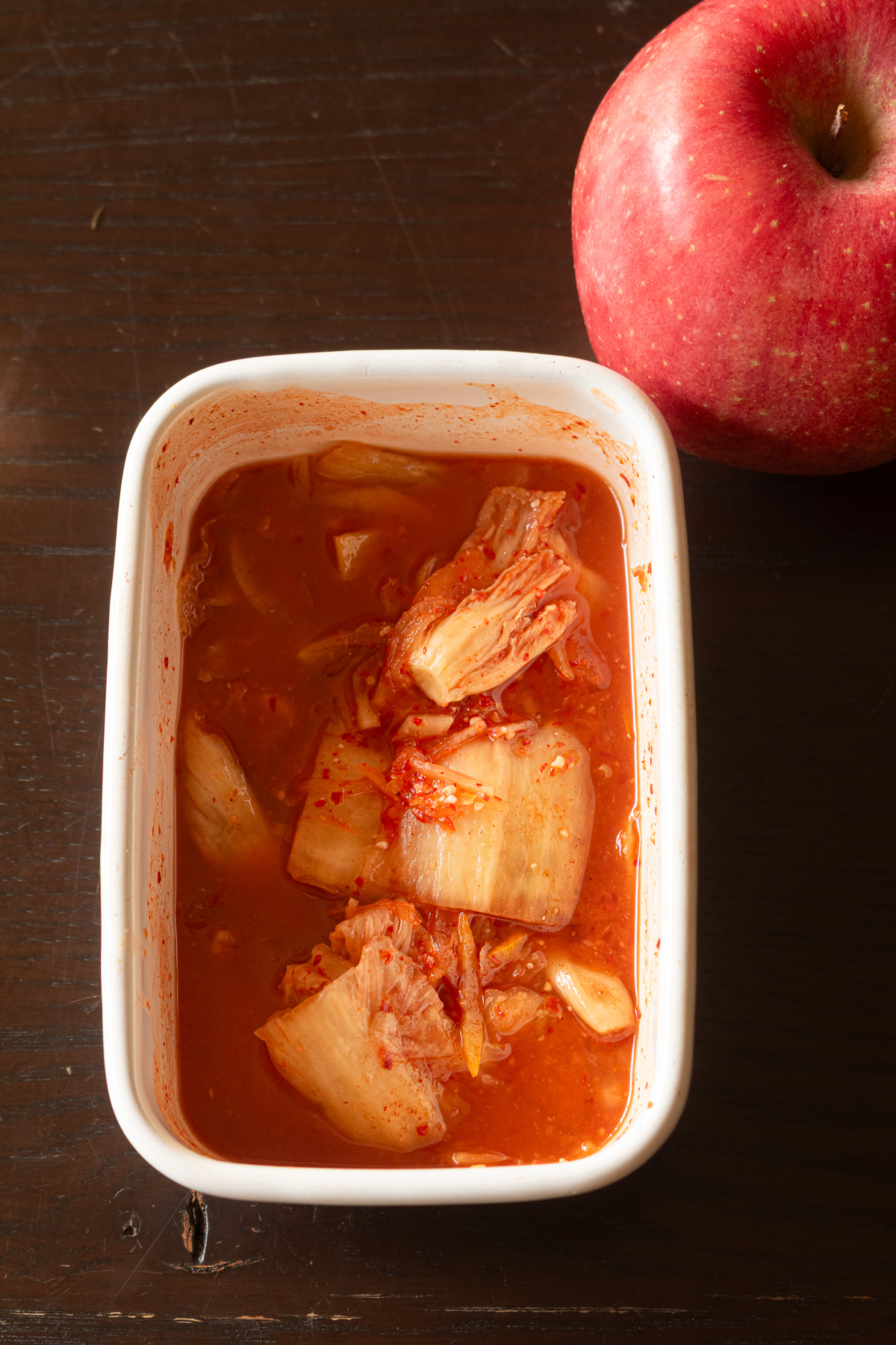 保存容器に入ったヴィーガン白菜ゆずキムチとりんご