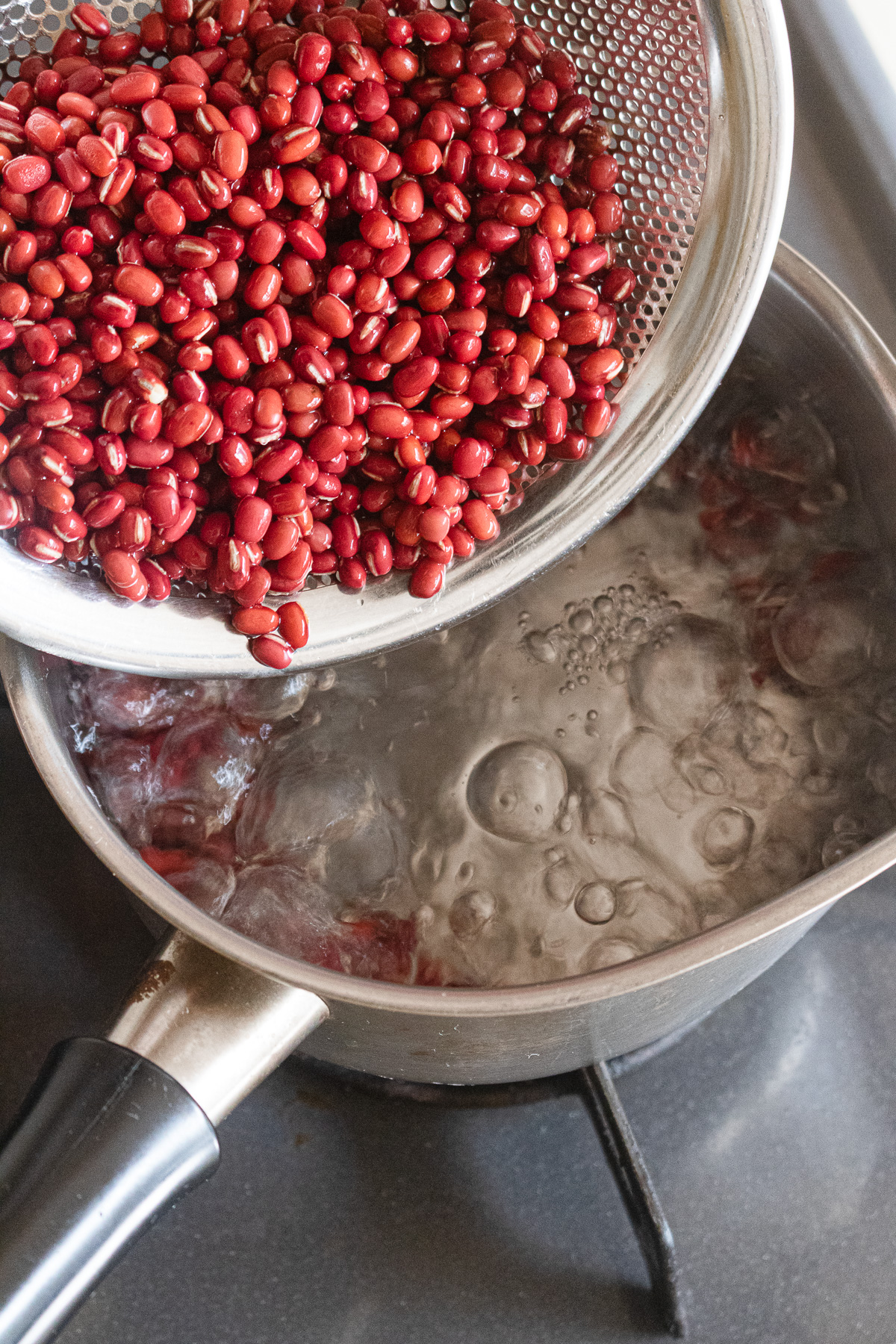 Adding rinsed dried adzuki beans to boiling water