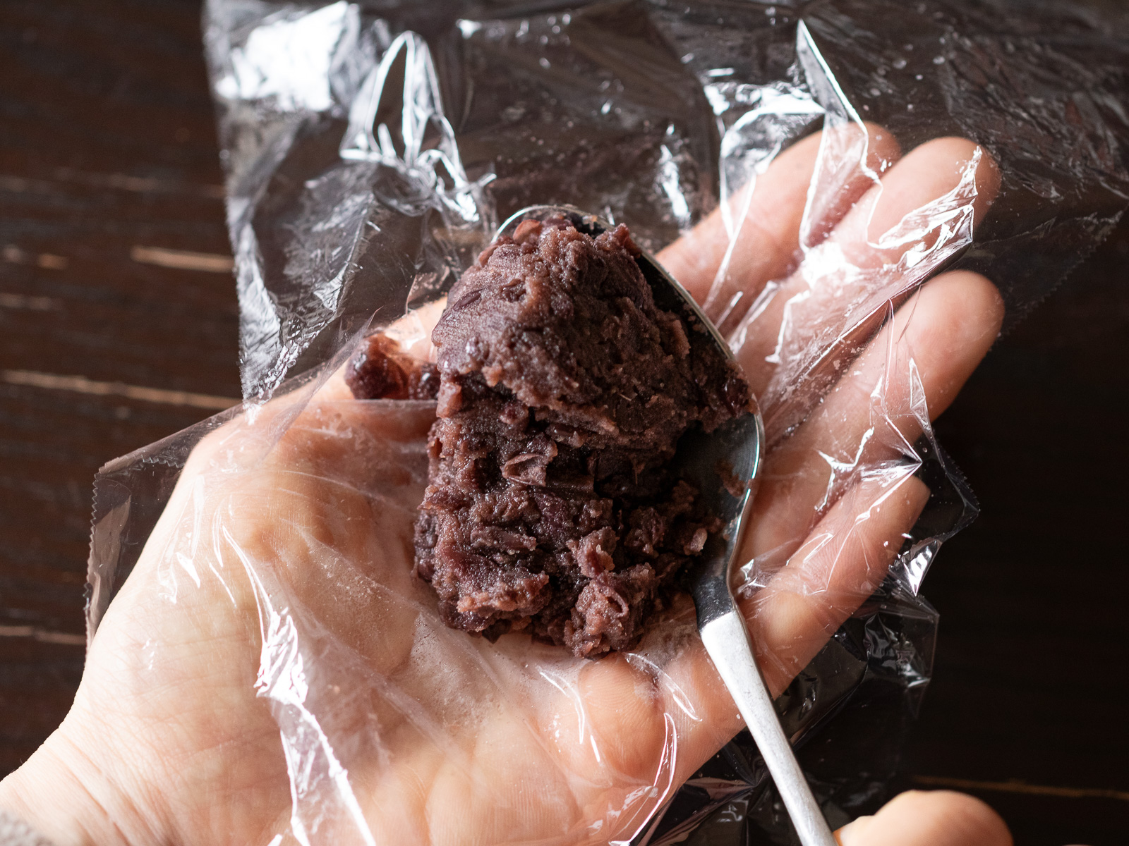 ラップの上に山盛りスプーンいっぱいのつぶあんをのせる。基本のおはぎの作り方