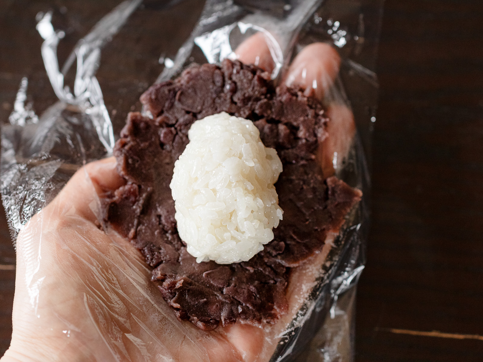 広げたあんこの中央に握ったごはんをおいたところ。基本のおはぎの作り方