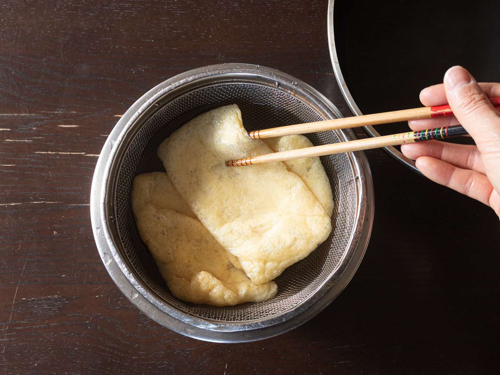 油揚げをザルにあげて湯を切る