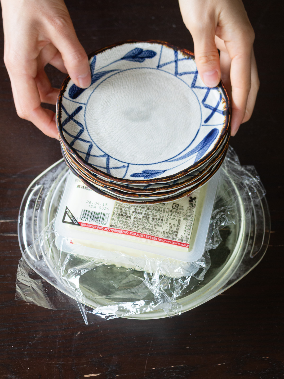 木綿豆腐の水切り方法：皿を重ねて重石を足し冷蔵庫で8時間以上水切りする