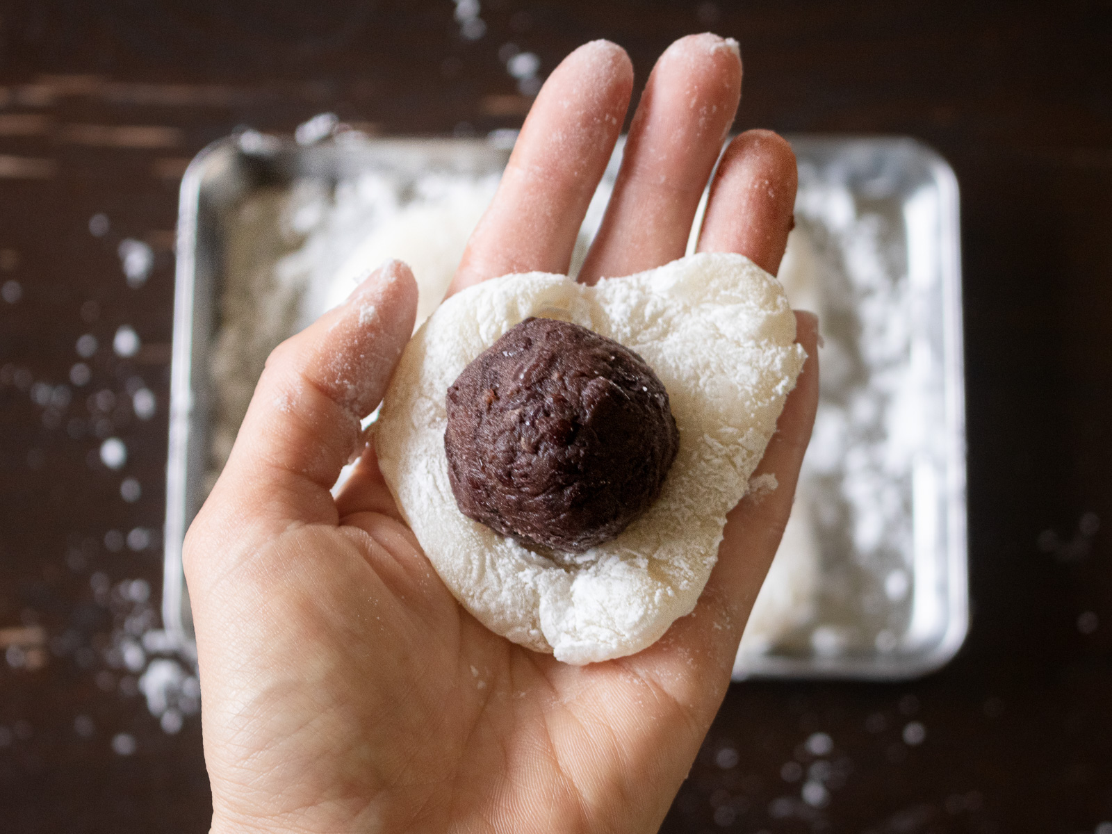 いちご大福の包み方①餅にいちごの頭を下にして、あんこ玉をのせる