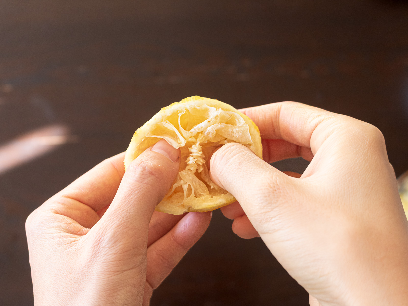 横半分に切ったゆずに親指を入れているところ