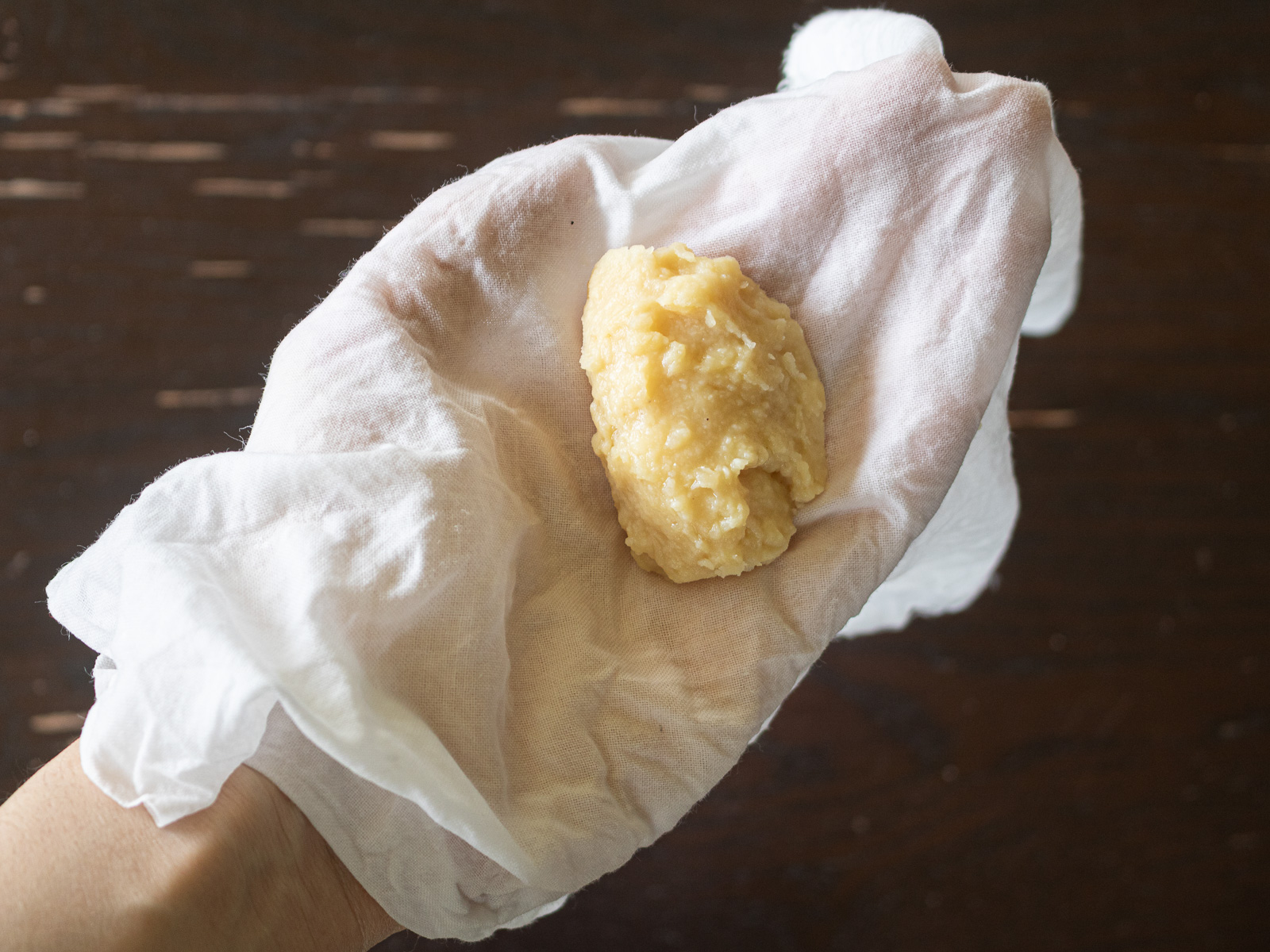 濡らして軽く絞った晒しの上に緑豆あんをのせて茶巾絞りを作る様子。